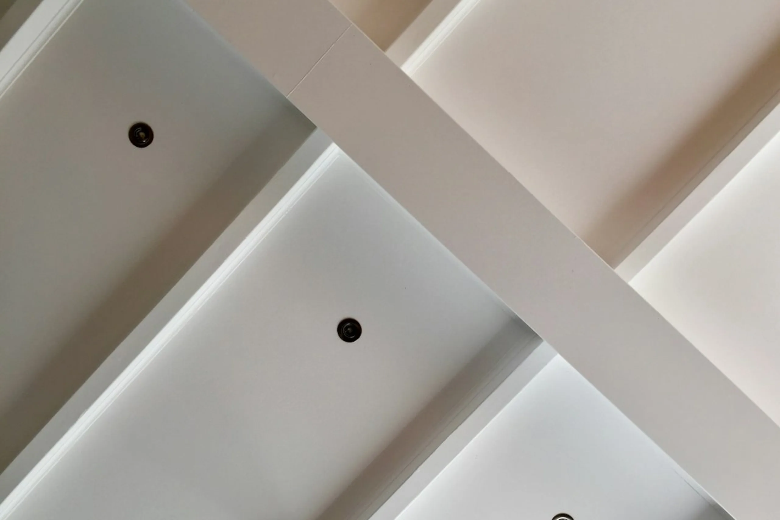 Lames de lambris PVC blanc en cours de pose sur des tasseaux fixés au plafond
