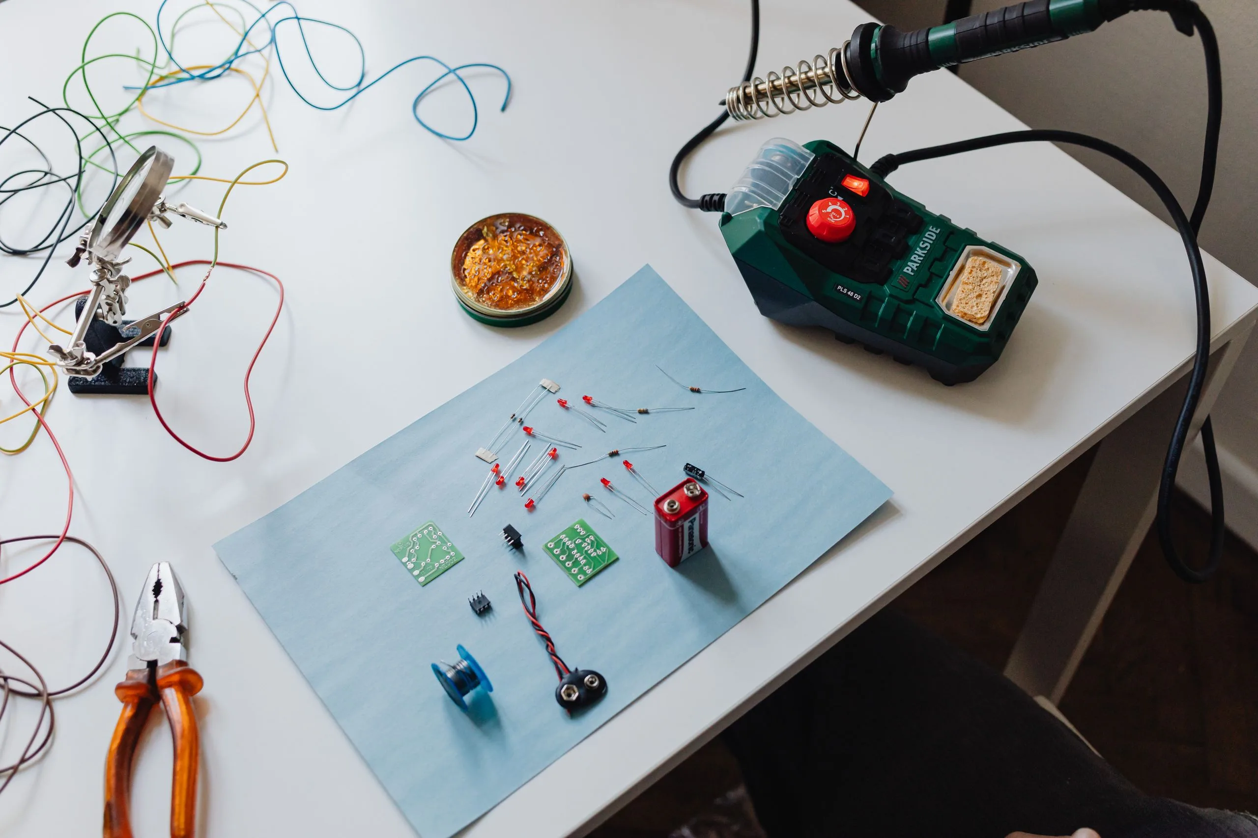 Station de soudure avec son fer posé sur le support, sur un établi de bricolage